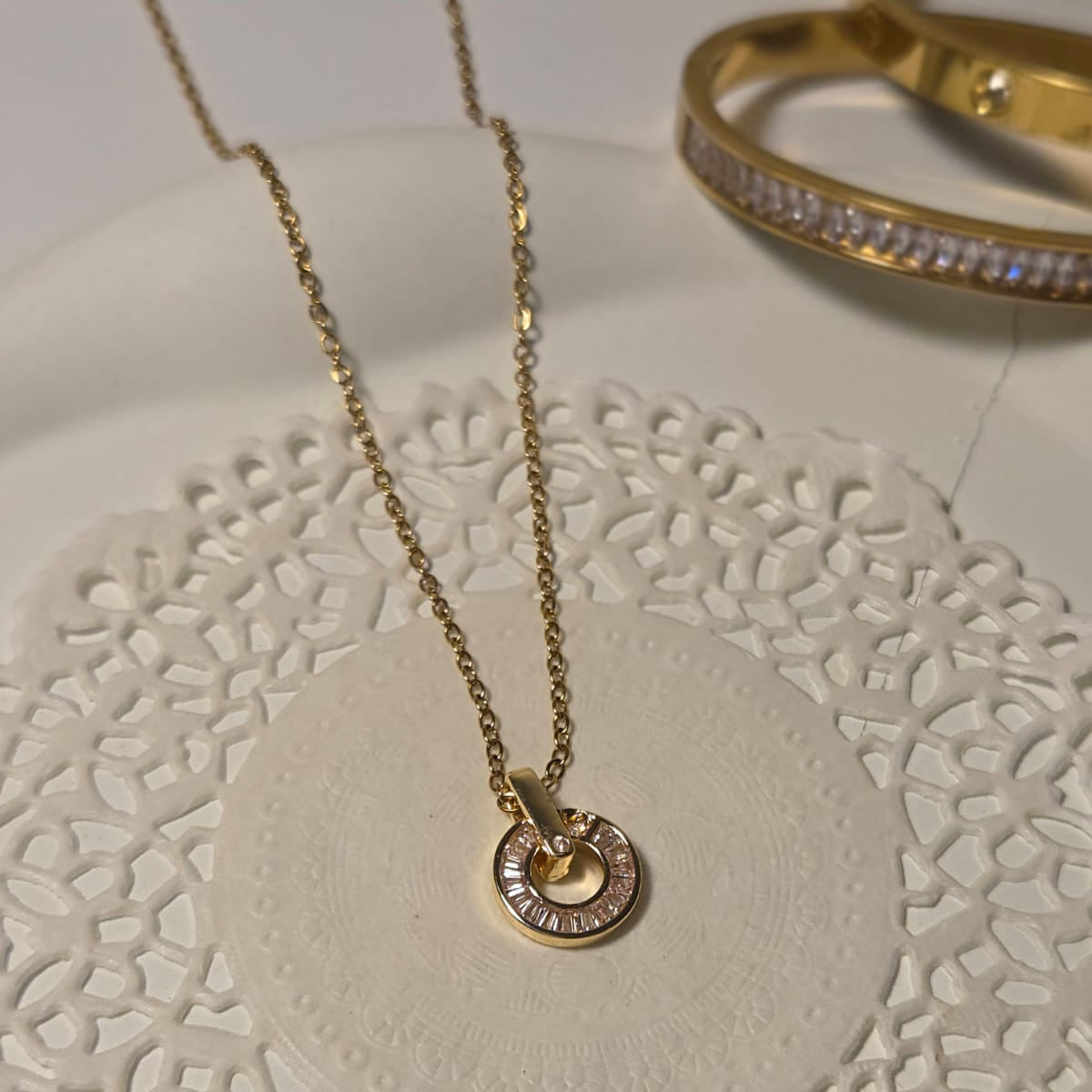 Gold necklace and bracelet on a decorative white surface