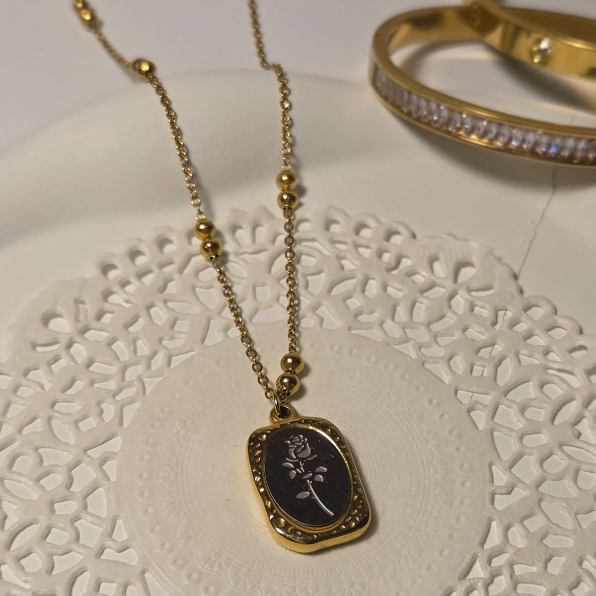 Gold necklace with a pendant on a white lace doily